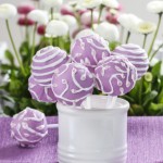 Lilac cake pops in white ceramic jar. White and pink daisies